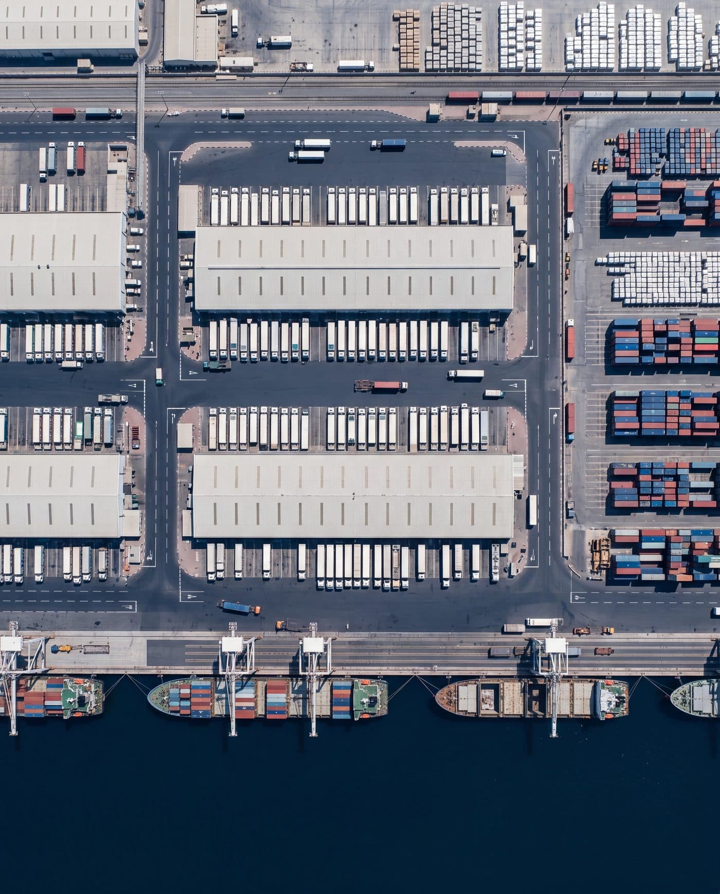 Aerial view of a UAE port — warehouses, truck fleet, container yards and vessels at berth, representing Credential Ship Services' network footprint